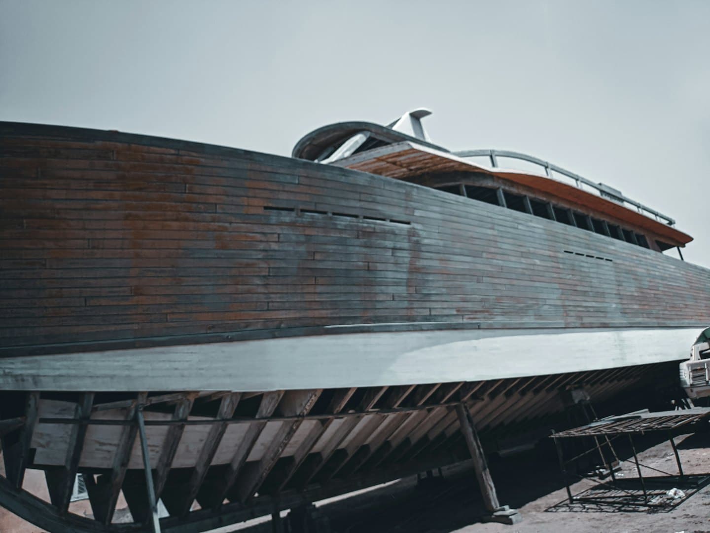 Un grande yacht di legno si trova su ponteggi in cantiere per riparazioni.