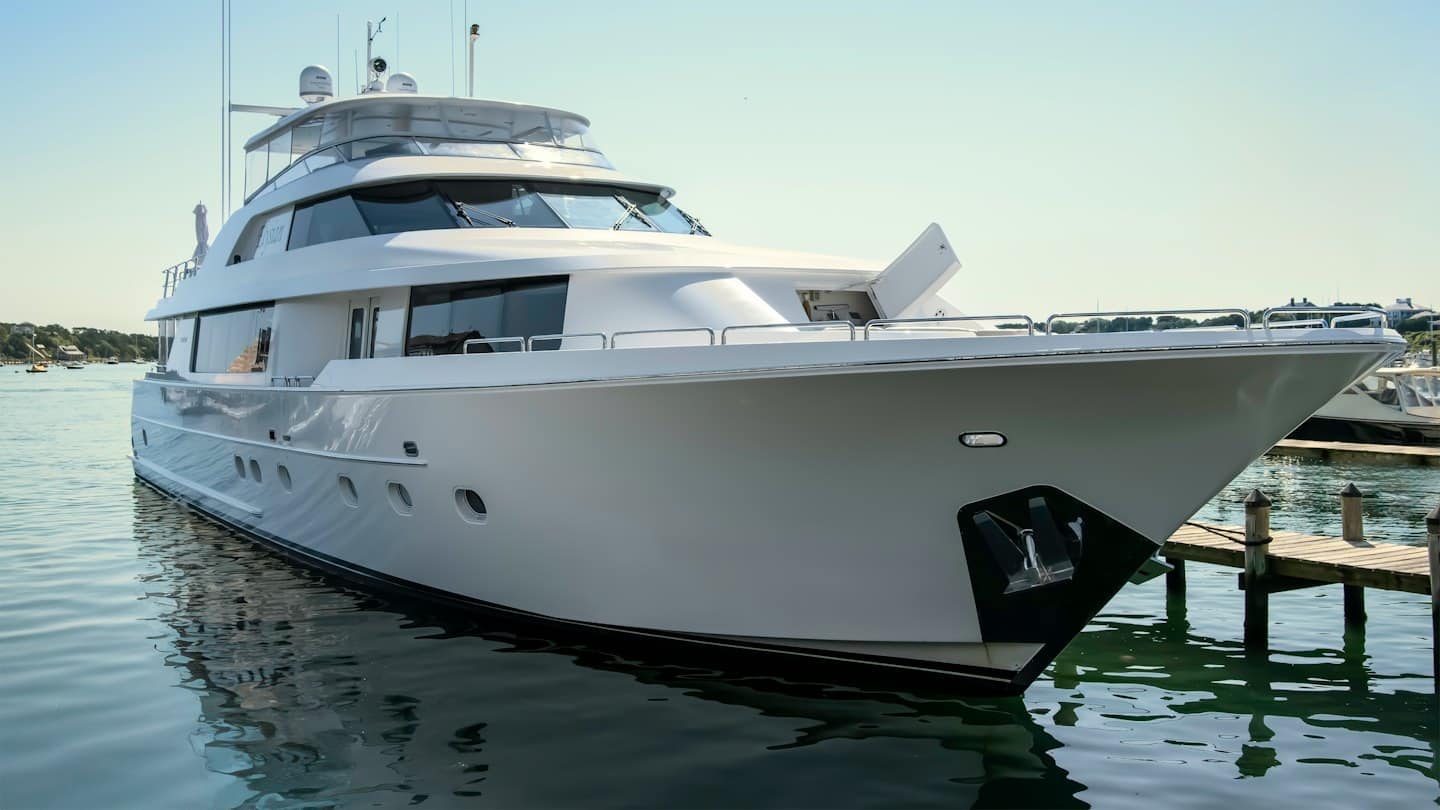 Uno yacht di lusso bianco è ormeggiato a un molo di legno.
