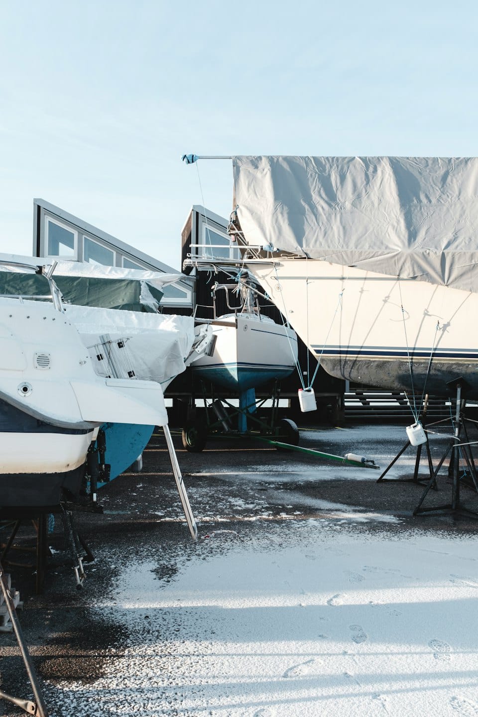 Barche coperte da teli in rimessaggio a secco in un cantiere navale.