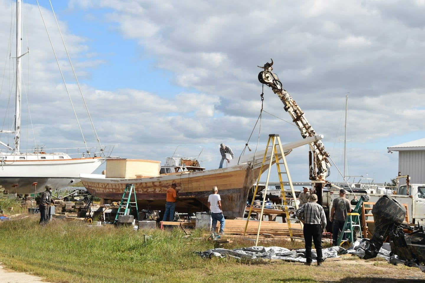 Operai riparano una grande barca di legno su ponteggi in un cantiere navale.